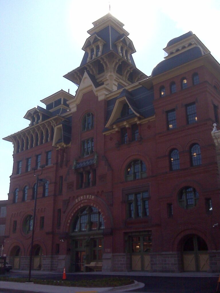 The ornate red-brick towers of the restored American Brewery building against a hazy sky