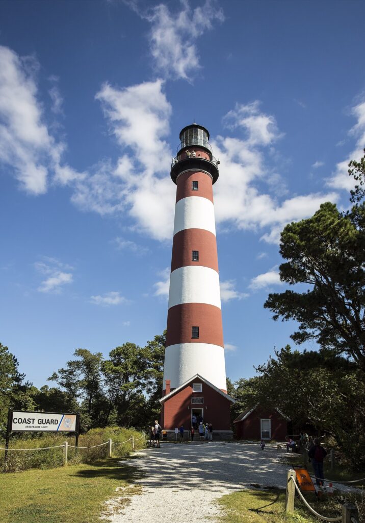 The red-and-white striped Assateague Lighthouse in Virginia against a blue sky with scattered clouds