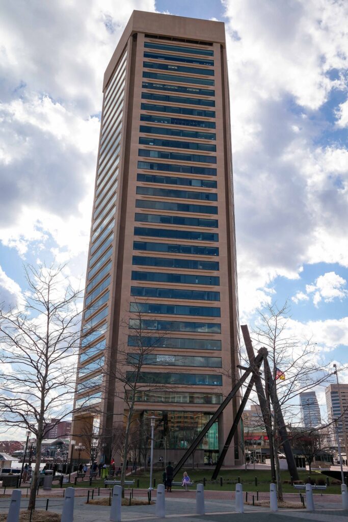 A tall pentagonal office tower with bands of windows rising against a partly cloudy sky