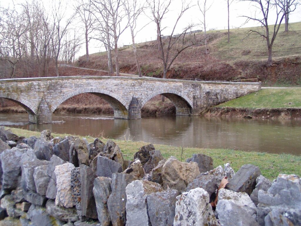 The three stone arches of Burnside Bridge over Antietam Creek, with a stone wall in the foreground