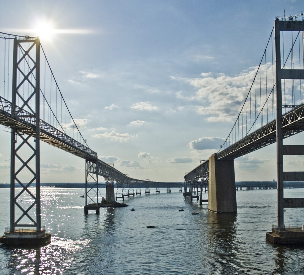 Looking up between the two suspension spans of the Bay Bridge from the water on a sunny day