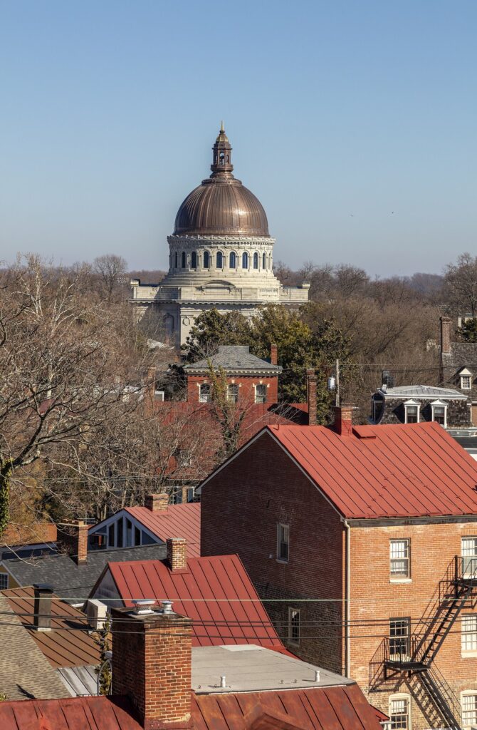 The copper dome of the Naval Academy Chapel rising above red-roofed brick buildings downtown