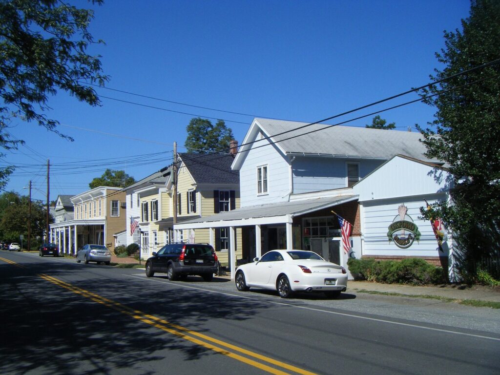 A row of small white and yellow clapboard shops along a quiet street under a blue sky