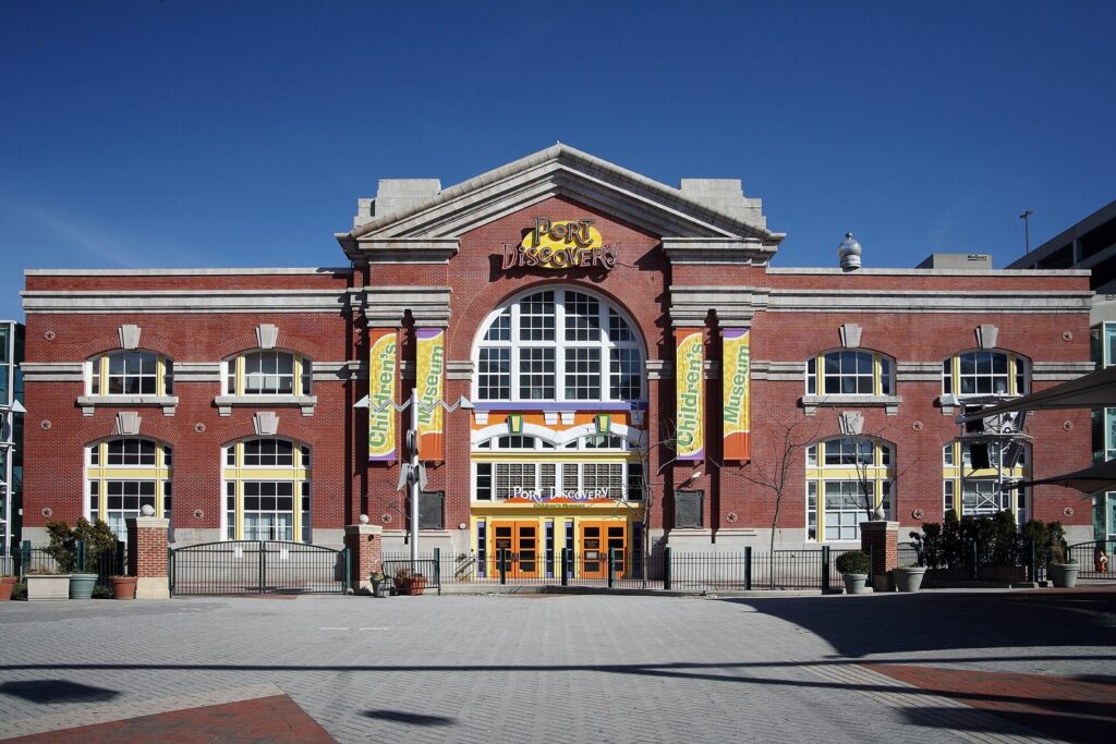The red brick facade of Port Discovery Children's Museum with arched windows and colorful banners