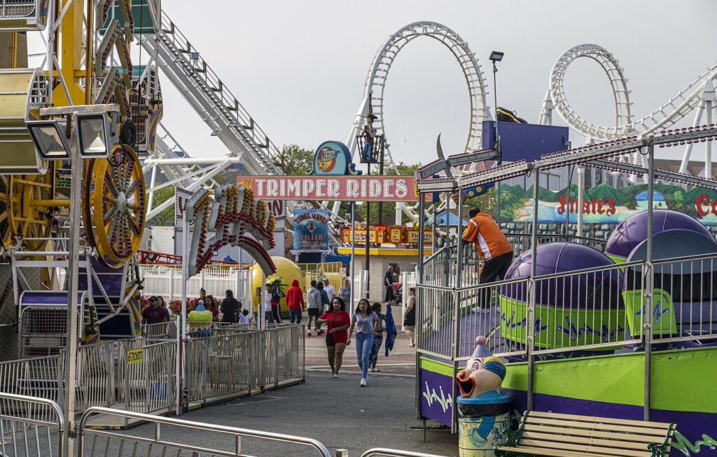 The Trimper Rides sign with a looping roller coaster and spinning rides behind it