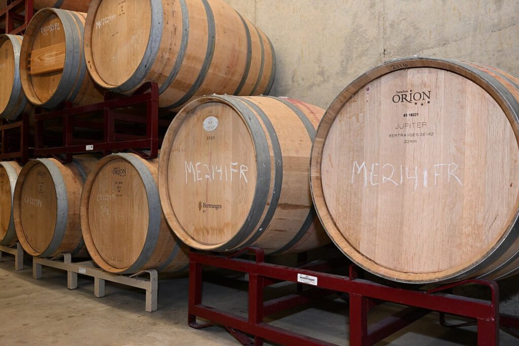 Oak wine barrels stacked two high on red steel racks in a cellar