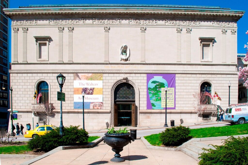 The pale stone Italianate facade of the Walters Art Museum with banners by the entrance