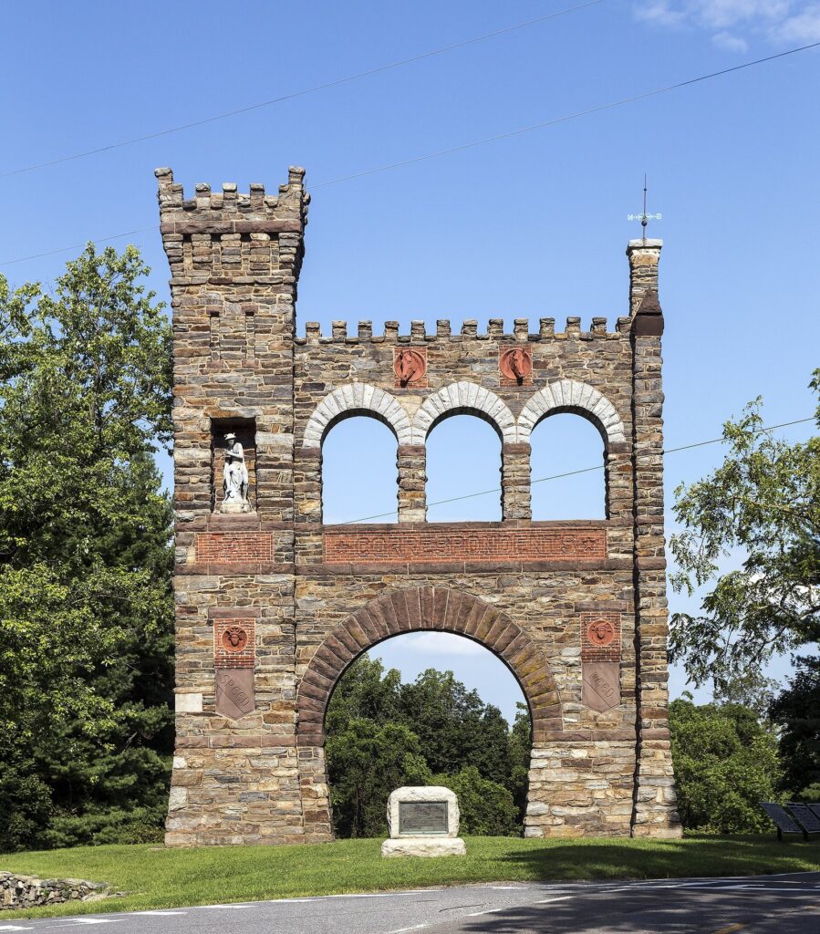 The tall stone War Correspondents Memorial Arch with three upper arches and a crenellated tower against a blue sky
