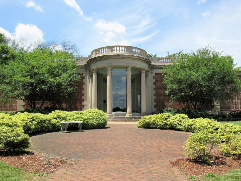 The columned entrance of the Washington County Museum of Fine Arts behind a circle of shrubs and a brick walk